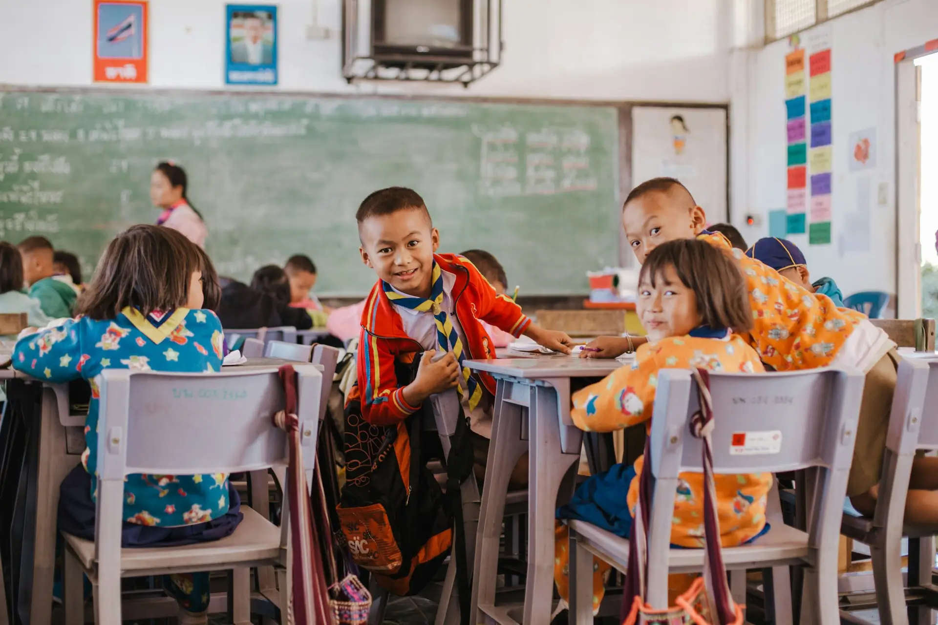 A kid in a red jacket is getting out of his chair and is really excited